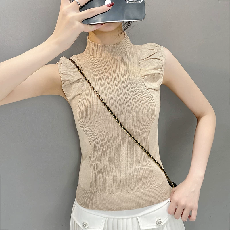 Front view of beige ribbed knitted top with high neck and ruffled shoulders